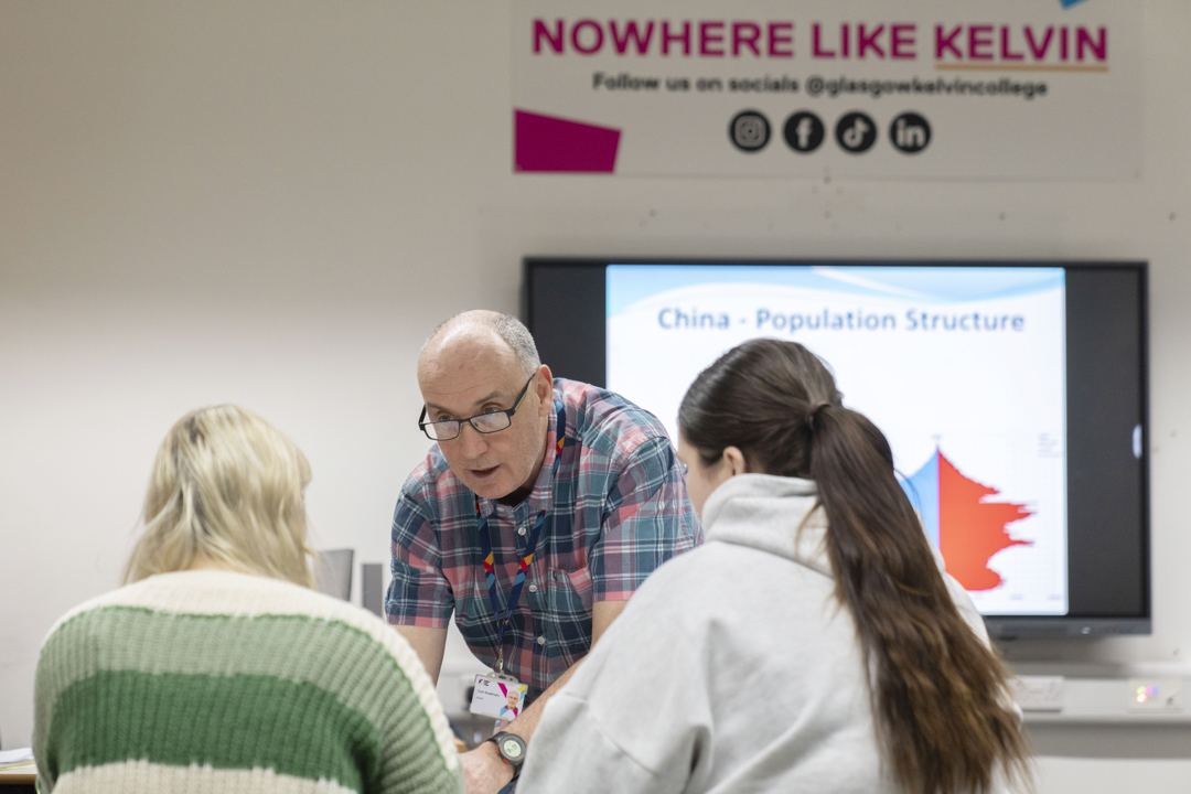 Friendly one-to-one teaching moment between lecturer and students at Glasgow Kelvin College.