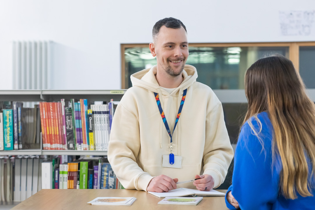Student receiving support from a staff advisor at a desk in the Glasgow Kelvin College library.