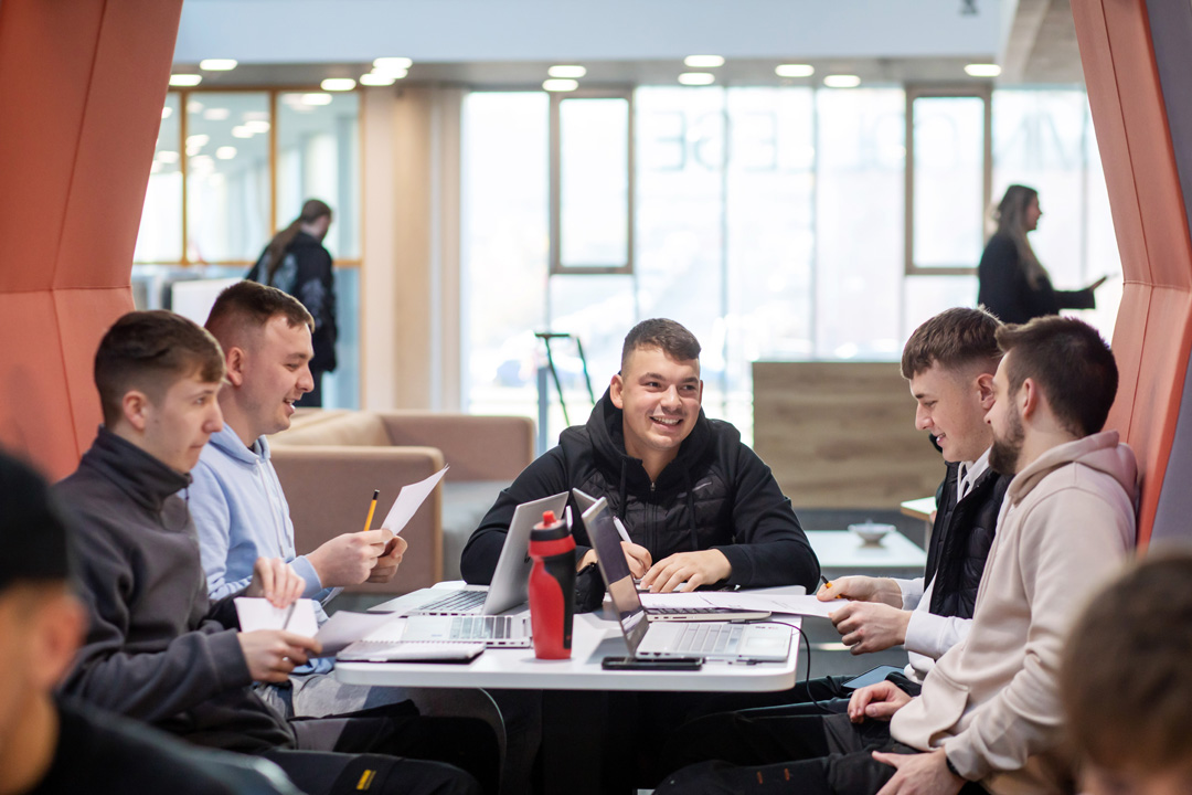 Group of male students working together on laptops and worksheets in a modern study pod at Glasgow Kelvin College Springburn campus