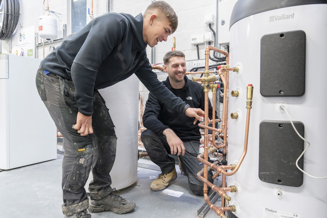Student working on a plumbing installation board with copper pipes at Glasgow Kelvin College as part of the Green Academy training programme.