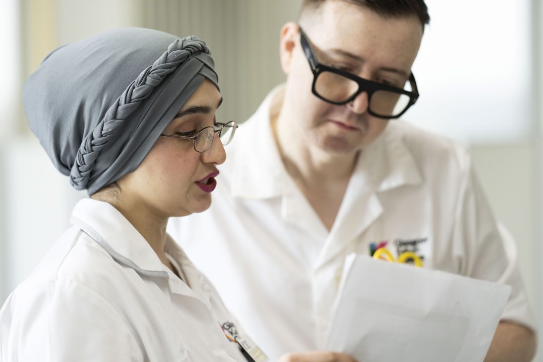 Close-up of two healthcare students reviewing patient notes in a practical classroom setting.