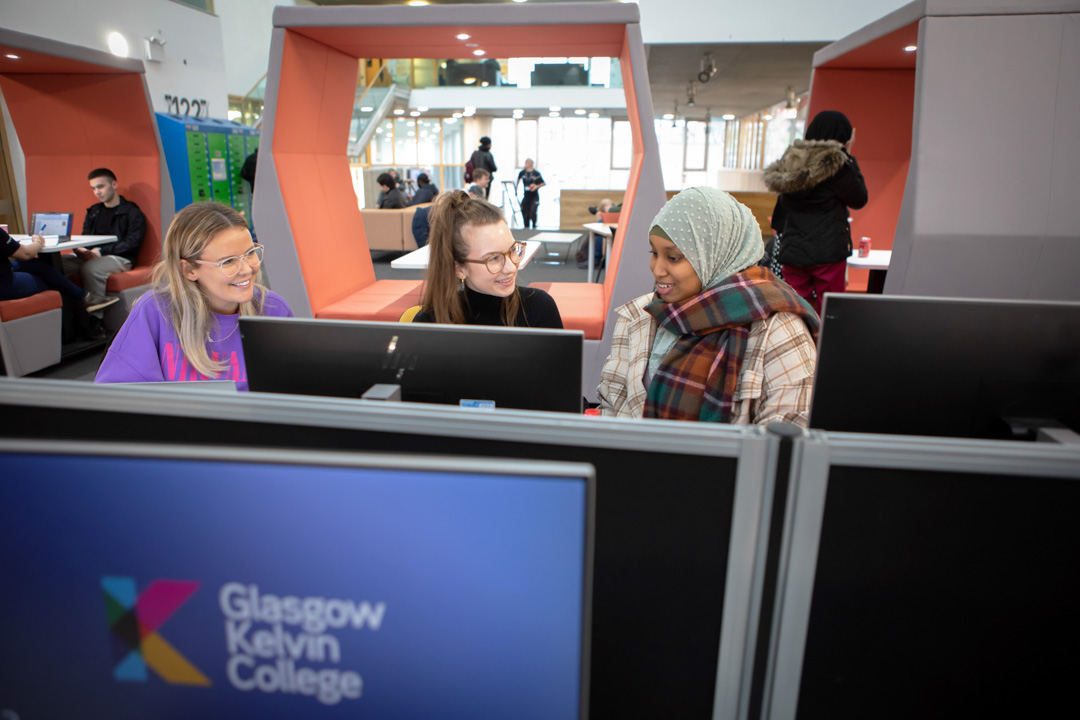 Three students using desktop computers and working together in the Springburn campus library at Glasgow Kelvin College