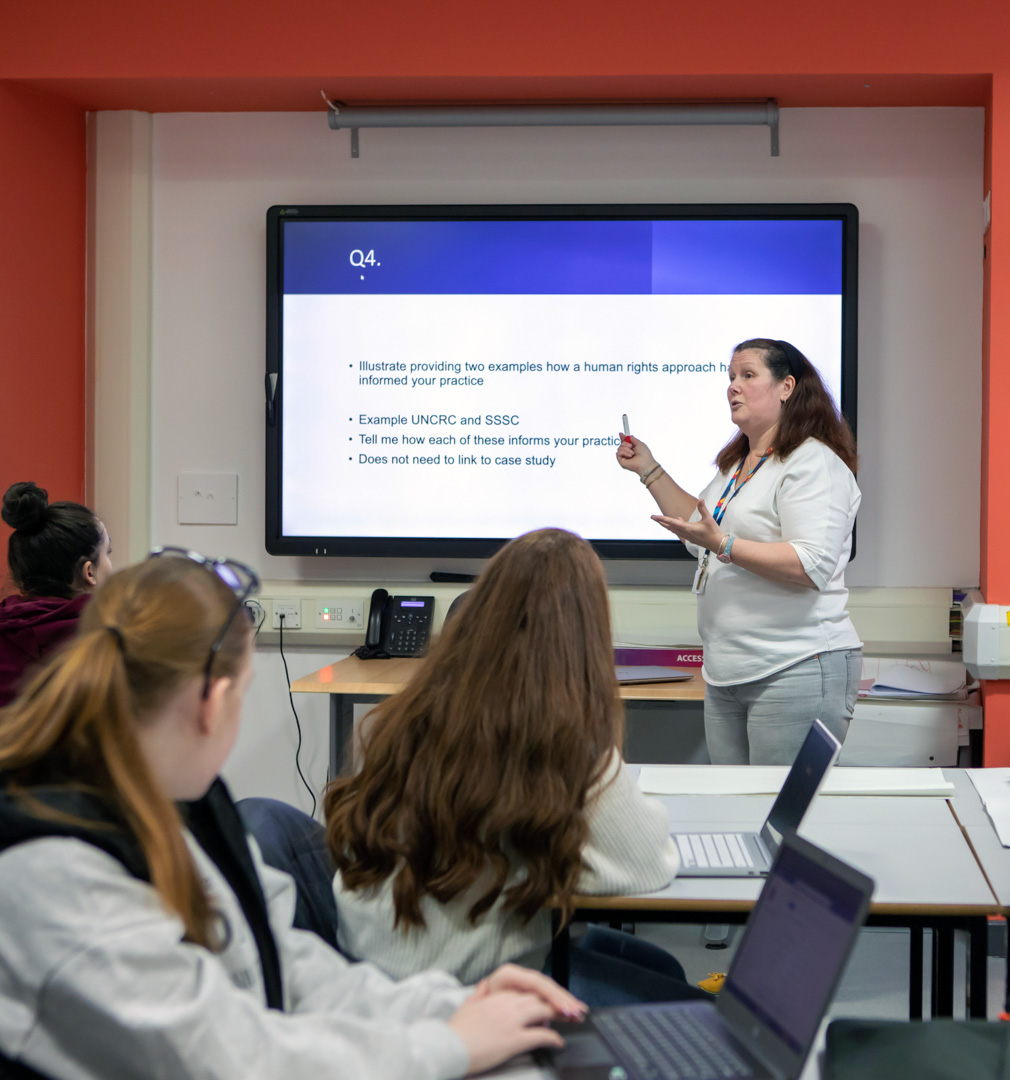 A lecturer at Glasgow Kelvin College leading an engaging discussion with students, exploring human rights approaches in practice.