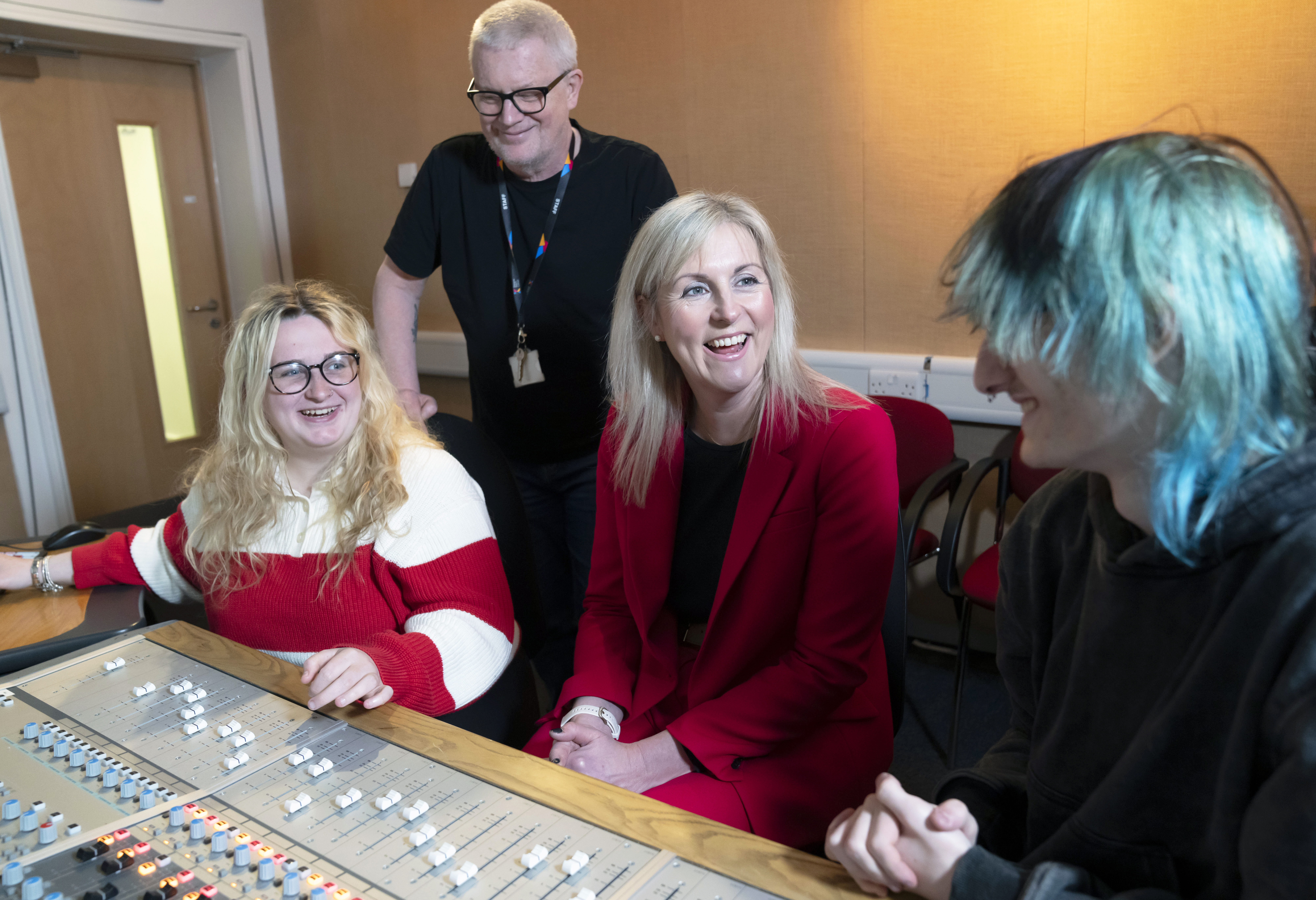 Principal Joanna Campbell chats with students and a staff member in a Glasgow Kelvin College recording studio, all smiling around a sound mixing desk.
