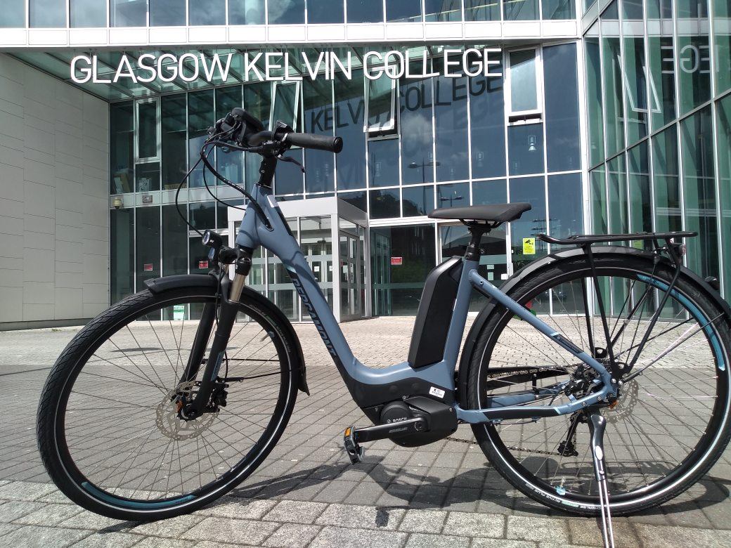 Electric bike parked outside the glass entrance of Glasgow Kelvin College Springburn campus.