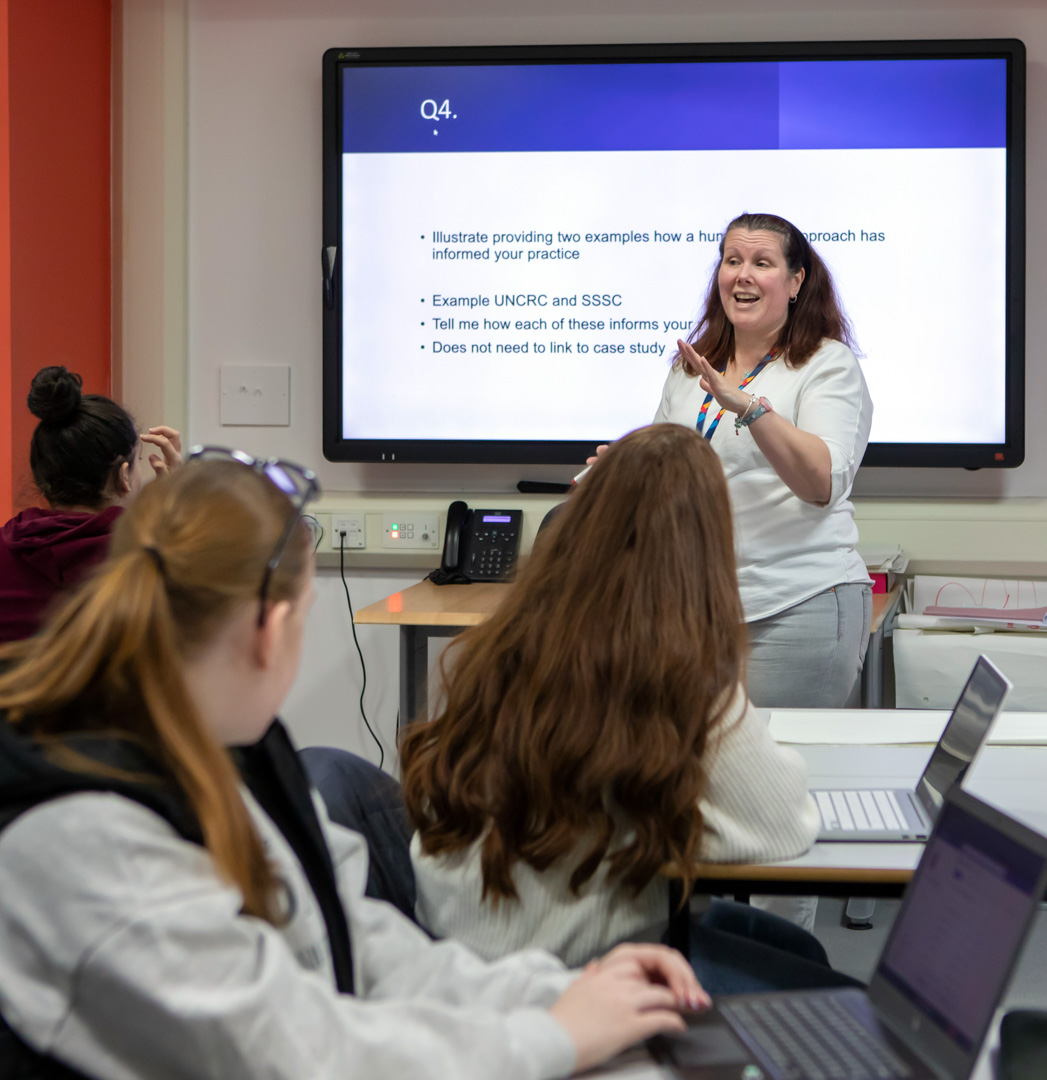 Students fully engaged in an interactive lesson at Glasgow Kelvin College, led by their enthusiastic lecturer encouraging lively classroom discussion.
