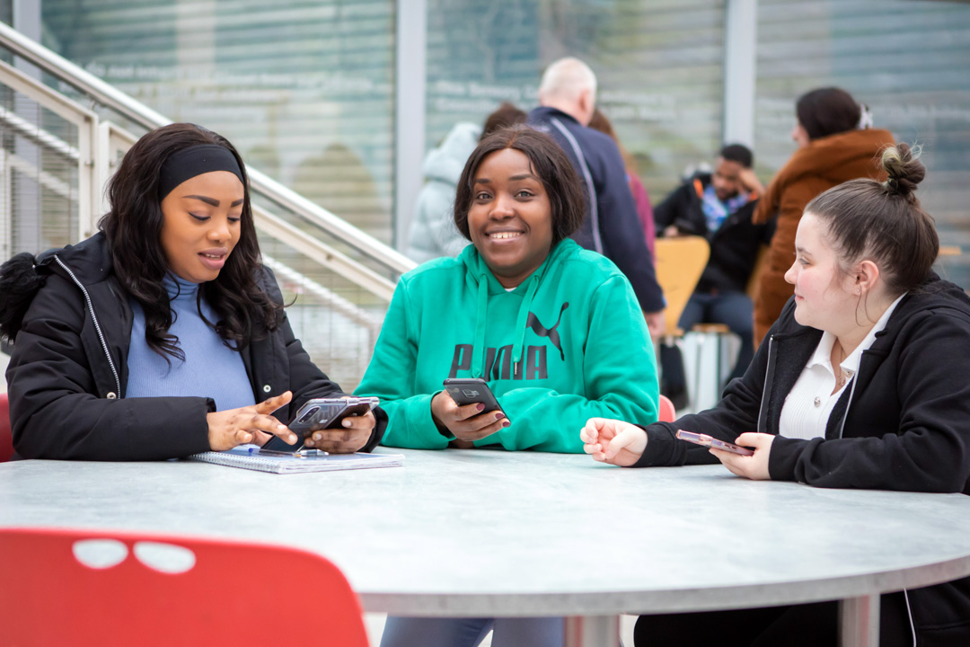 Student sitting in a communal area at Glasgow Kelvin College’s East End Campus, working or relaxing in a modern, shared space.