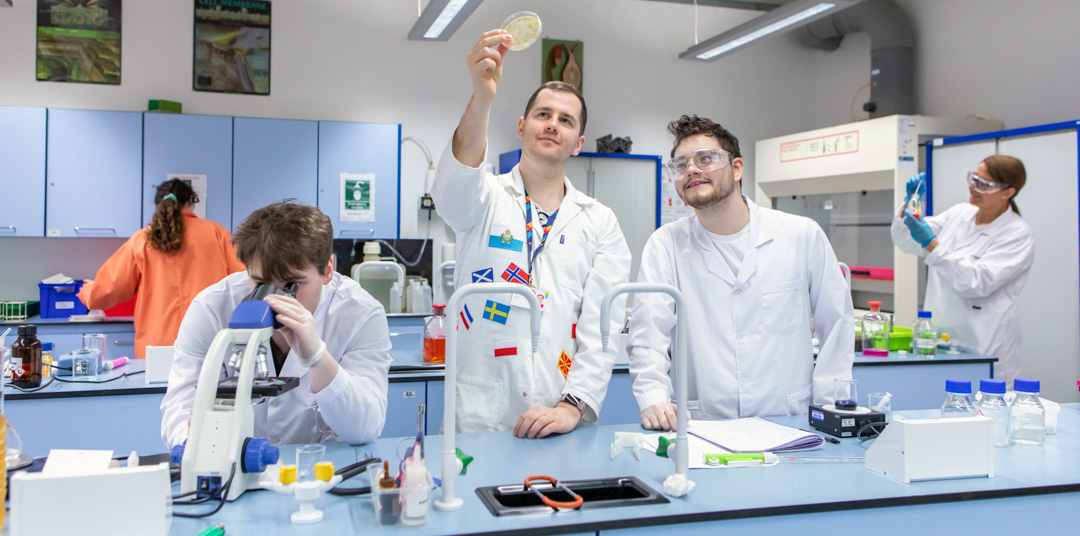 Science students and lecturer analysing samples with microscope and petri dish at Glasgow Kelvin College