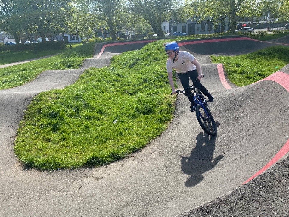 Student riding a BMX bike on an outdoor pump track during a sunny day, part of the Pathways to Employment Skills programme.