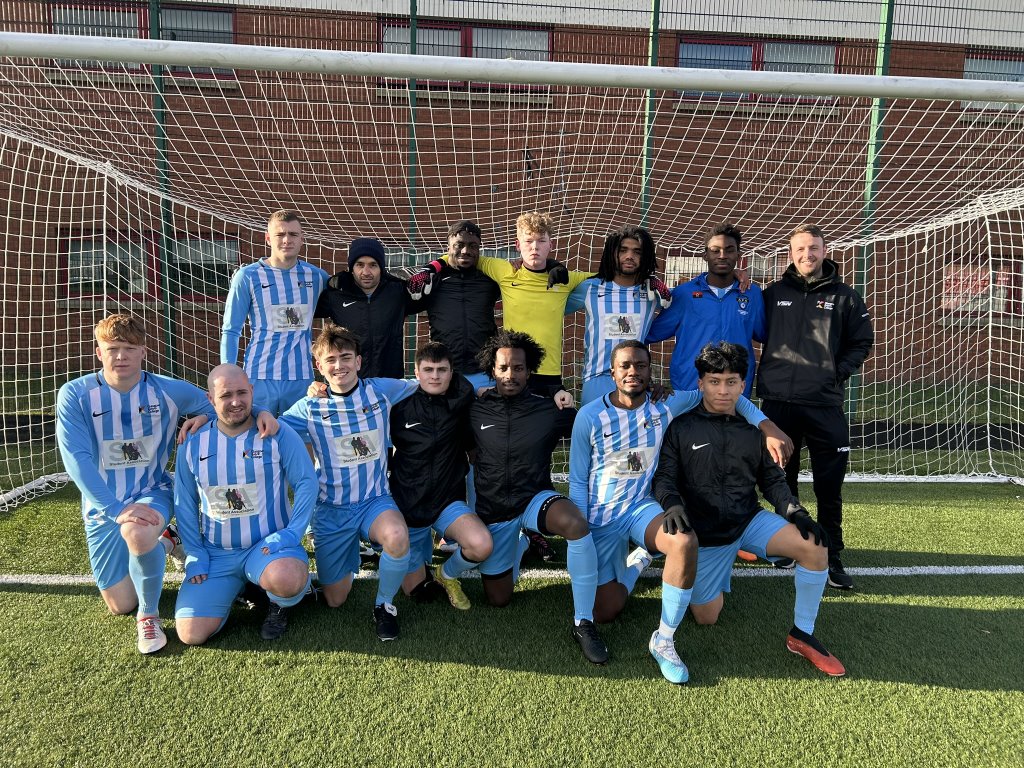 Glasgow Kelvin College men's football team posing together in front of a goal on the pitch, wearing blue and white kits.